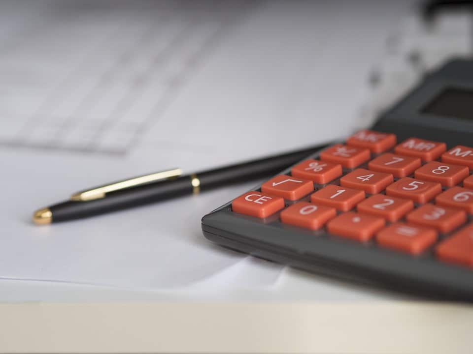 A pen and calculator on top of a spreadsheet going over self-funding