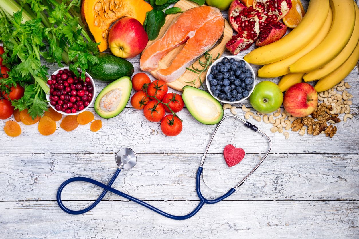 A stethoscope sitting in front of a pile of healthy fruits and veggies health insurance
