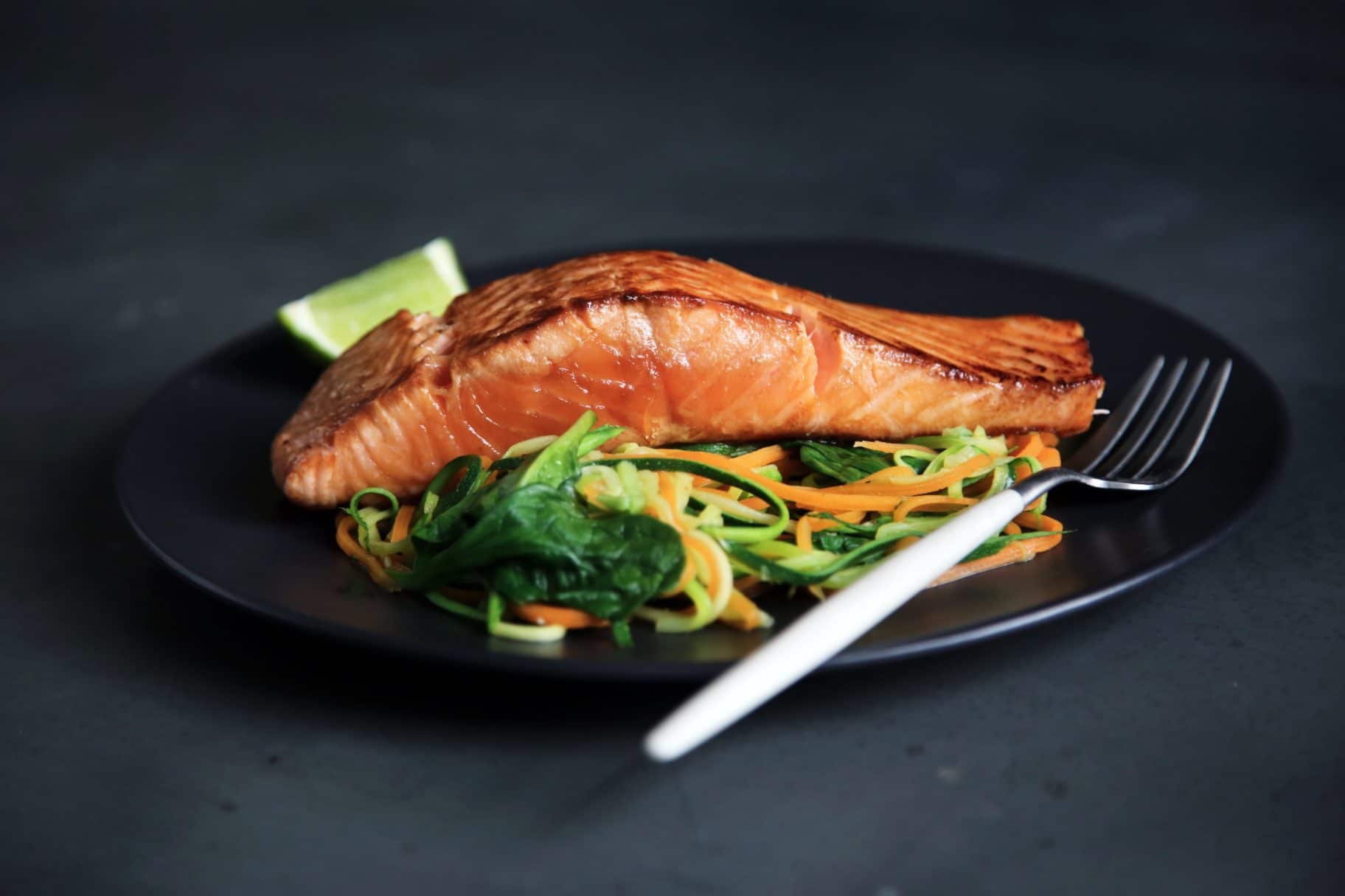 A plate with salmon resting on top of greens ketogenic diet