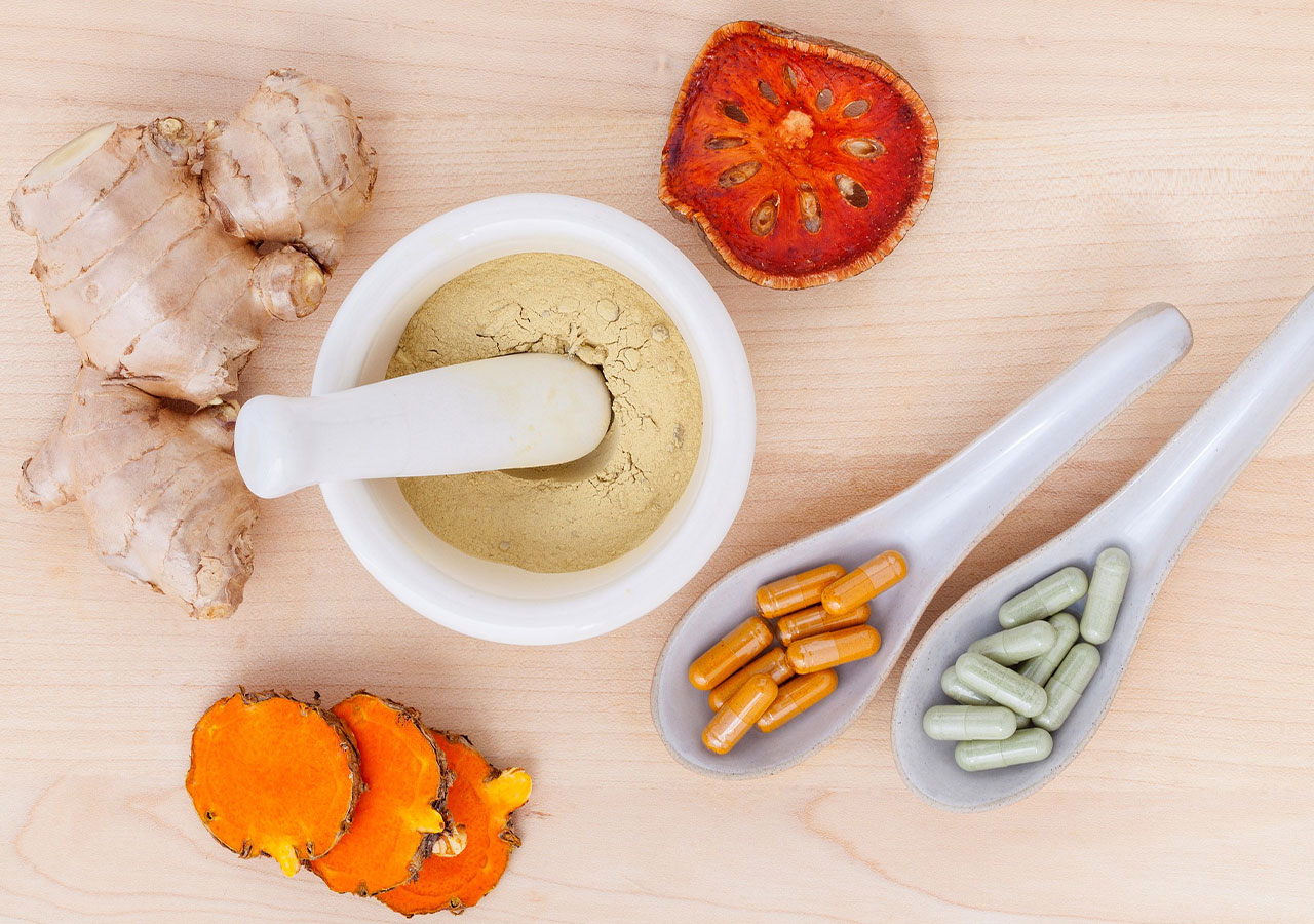 Probiotics such as tomatoes, pills, and ginger are on a counter top