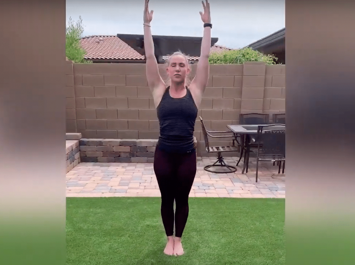 A female is in her backyard doing yoga poses