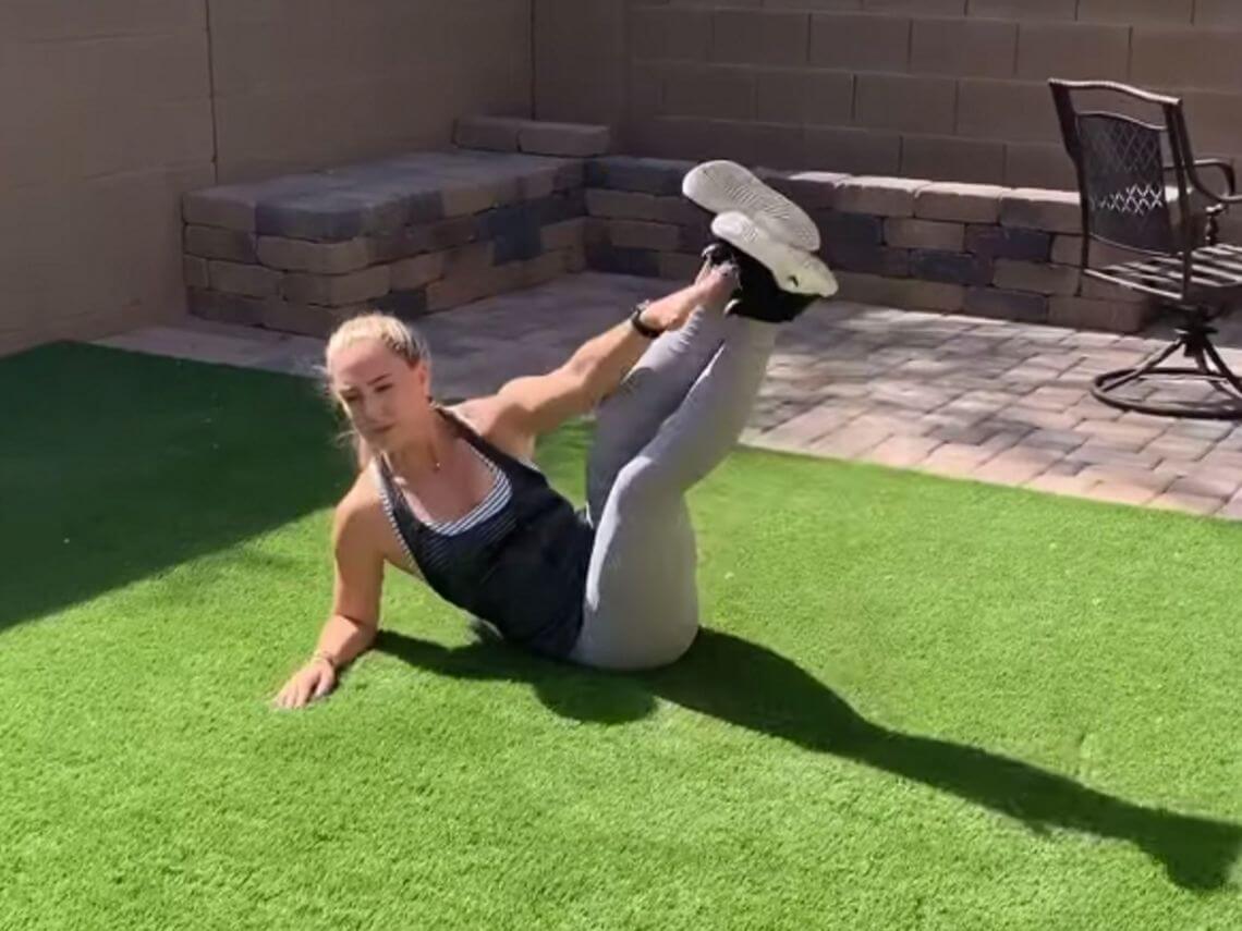 A woman is doing a workout in her backyard