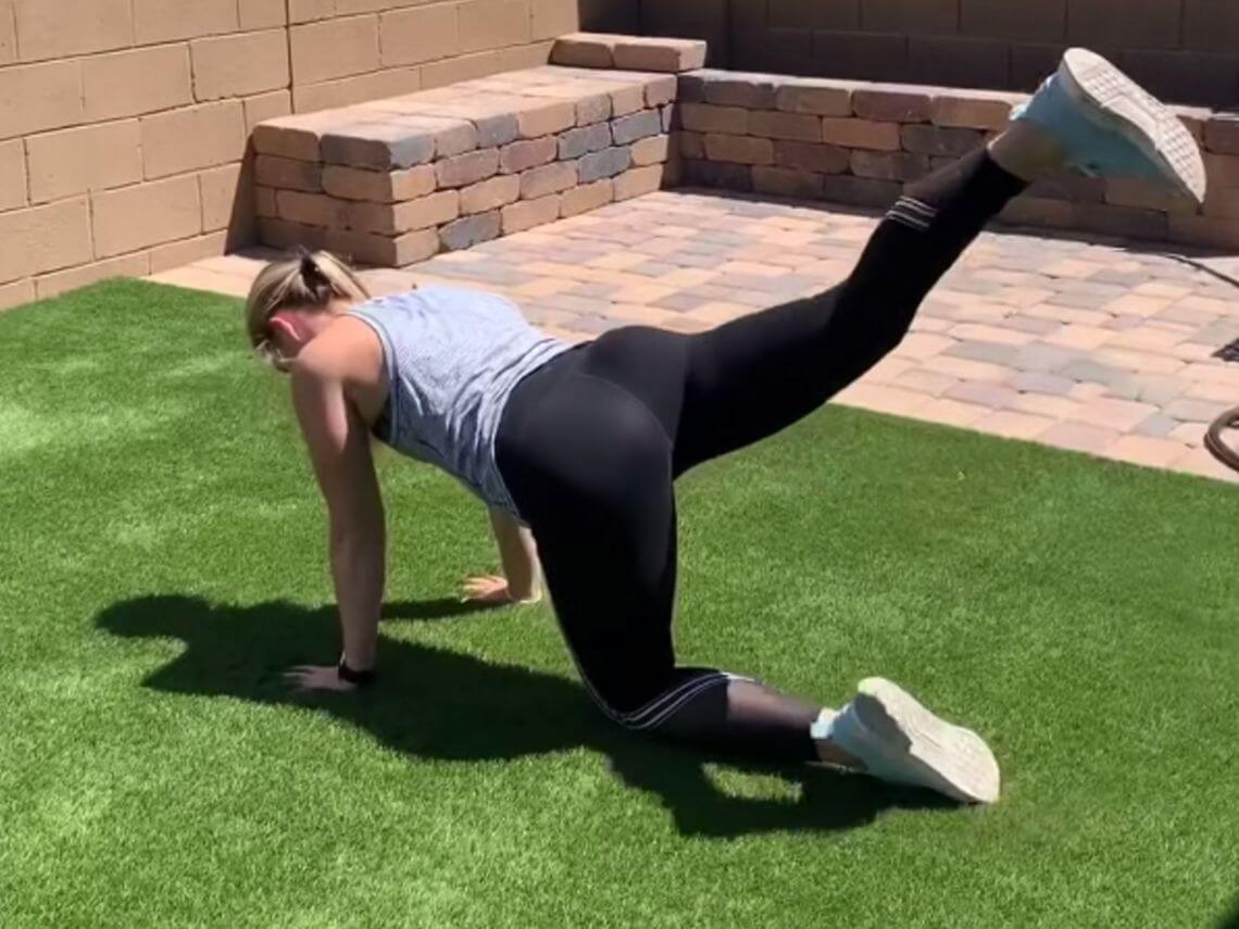A woman is in her backyard doing a full body workout